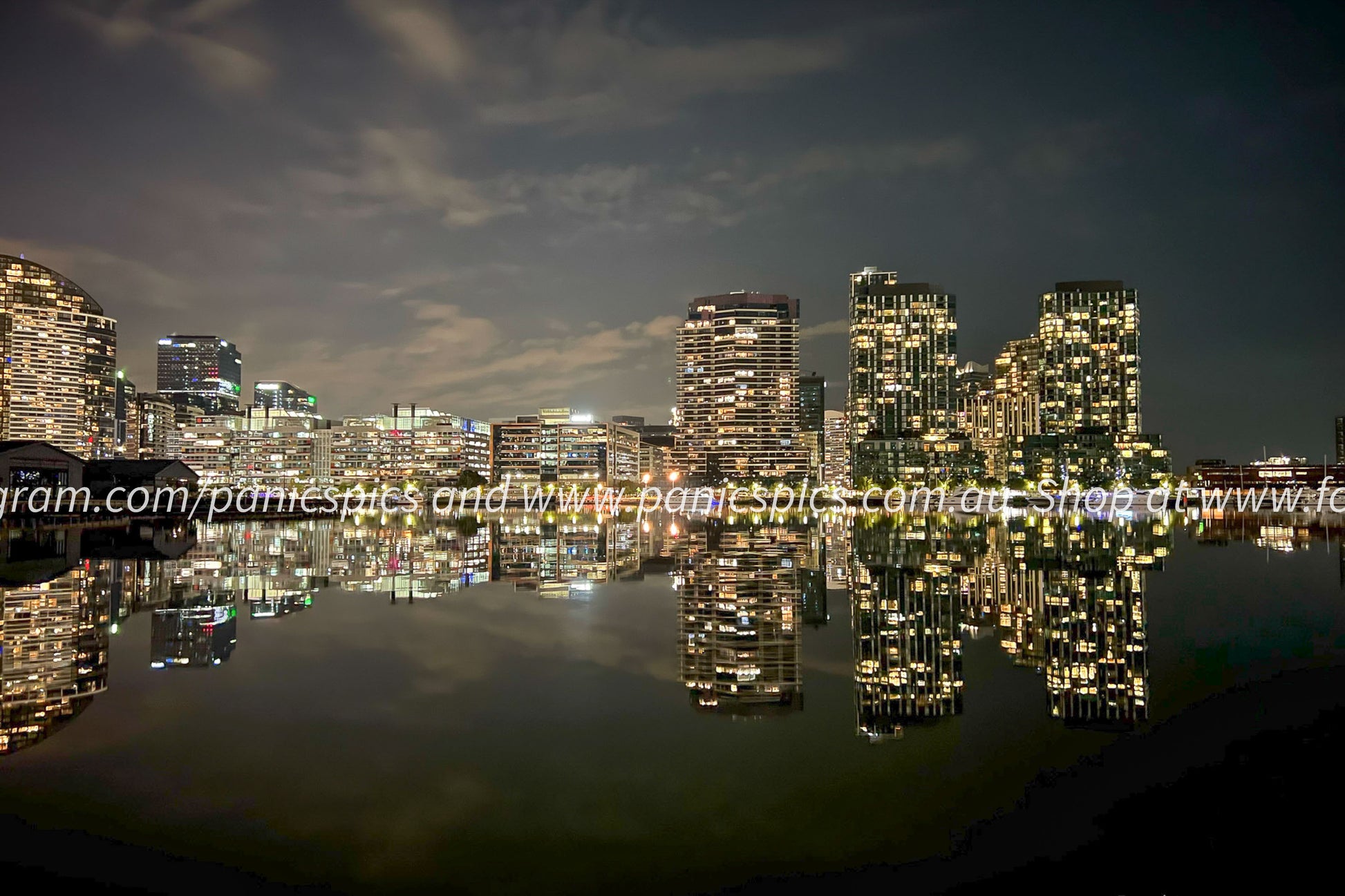 City skyline at night with illuminated buildings reflected in water