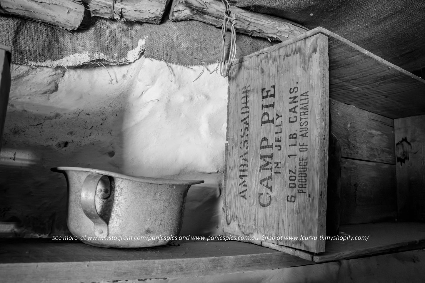 Vintage wooden crate labeled 'Camp Pie' with a ceramic pot underneath, in a rustic setting.