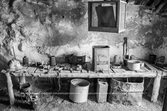 Vintage kitchen setup with rustic items on a wooden table against a textured wall.