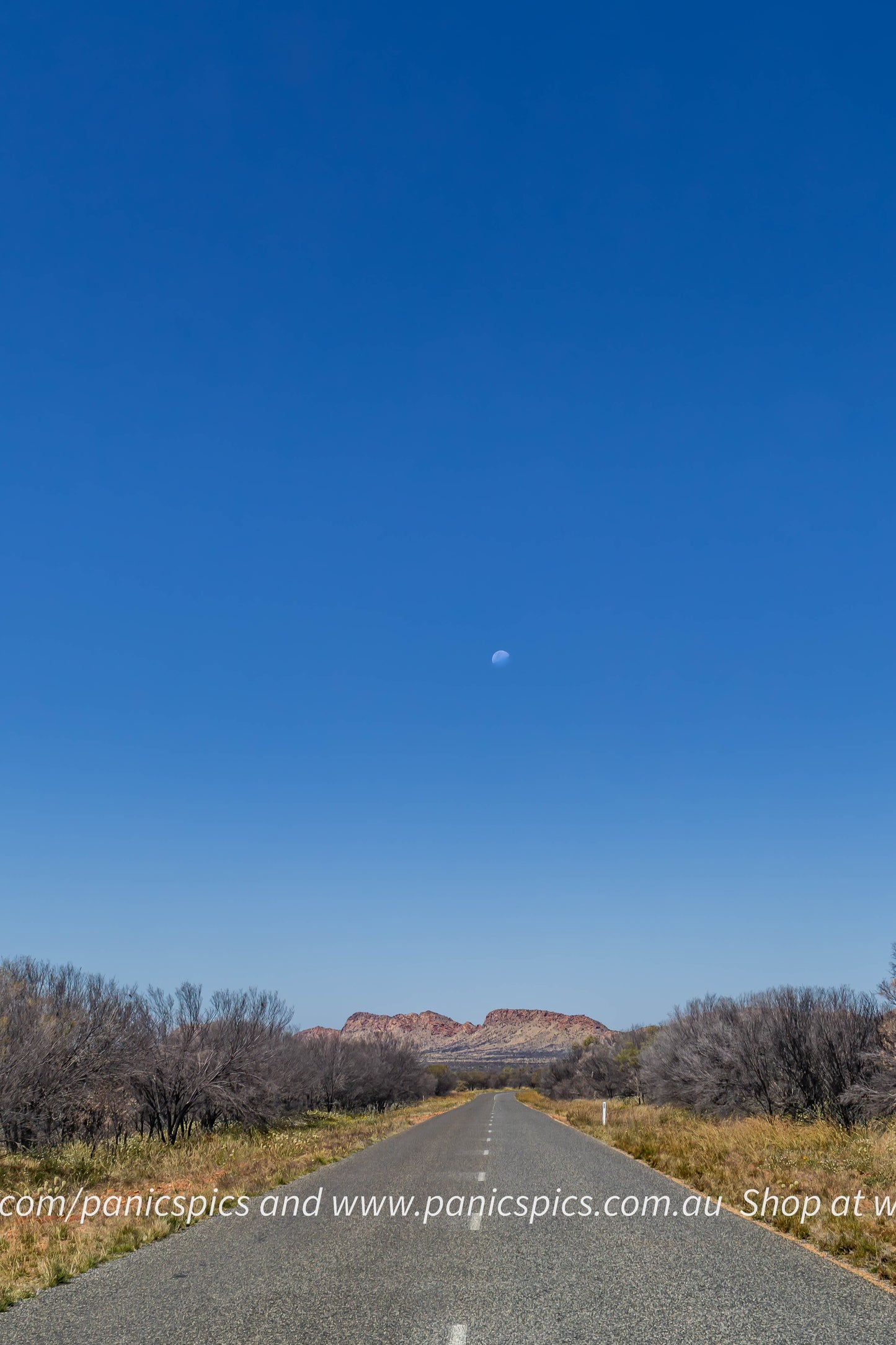 Long straight road stretching into the distance with a clear blue sky above.