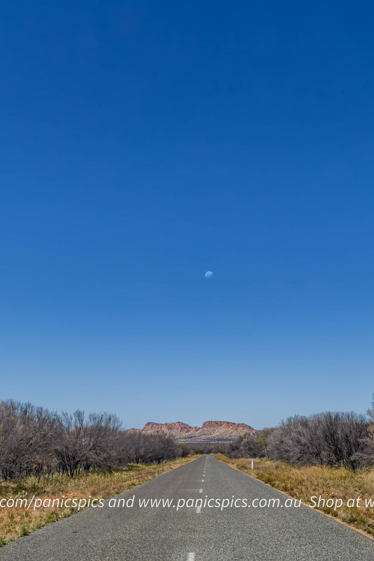 Long straight road stretching into the distance with a clear blue sky above.