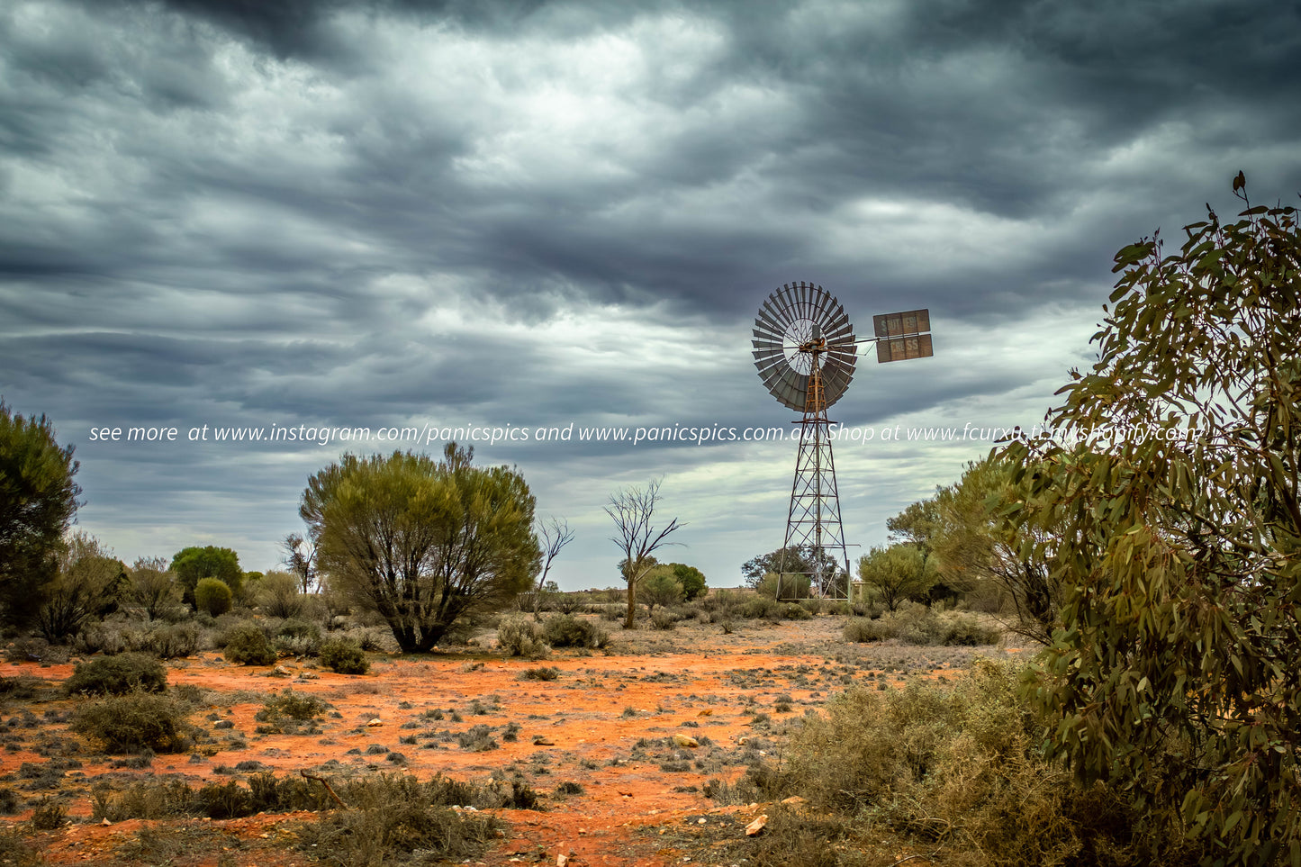 Desert landscape with a windmill under a stormy sky