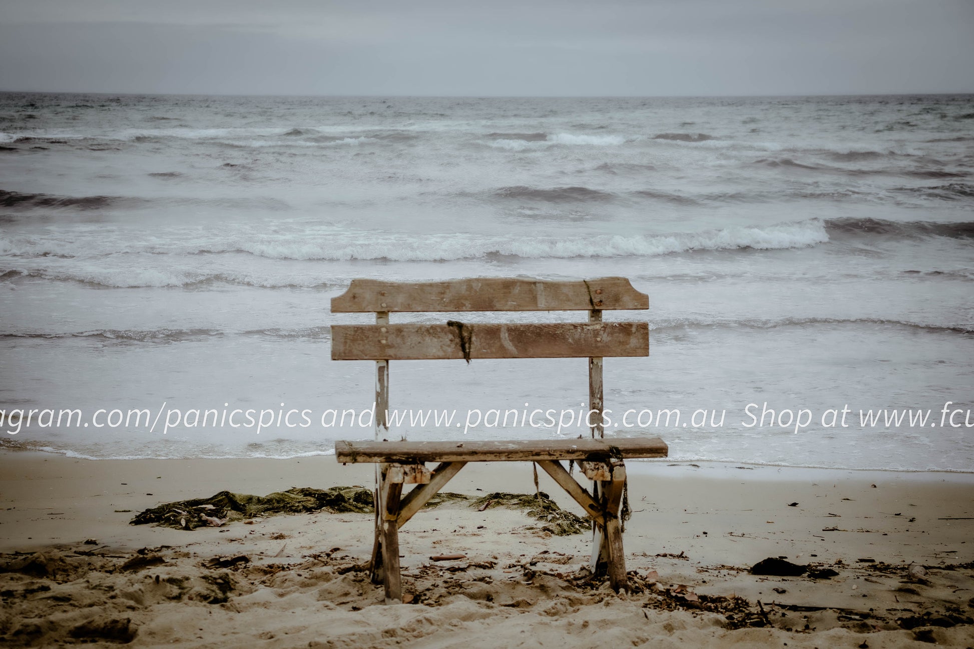 Wooden bench on a sandy beach with ocean waves in the background