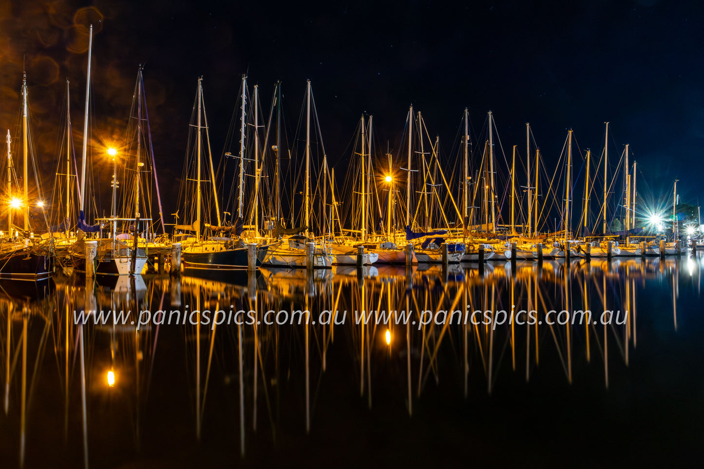 Marina at night with boats and masts reflected in the water