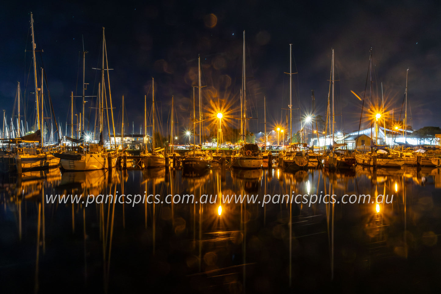 Marina at night with boats and lights reflecting on water