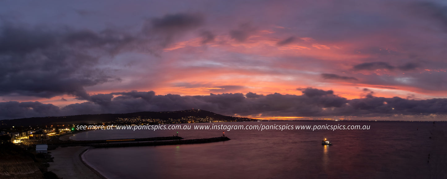 Sunset over a coastal area with a beach and buildings.